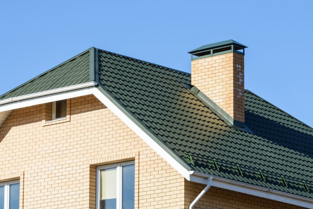 Brick House With Green Metal Shingle Roofing And Snow Guards