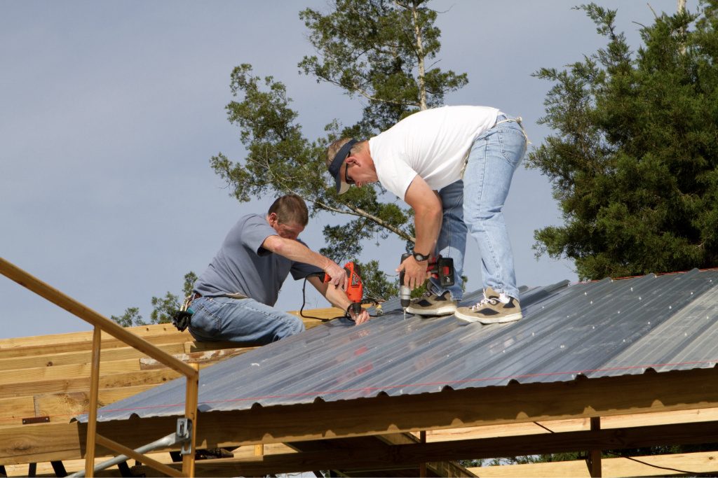 Workers Installing Ridged Metal Panels On A Barn